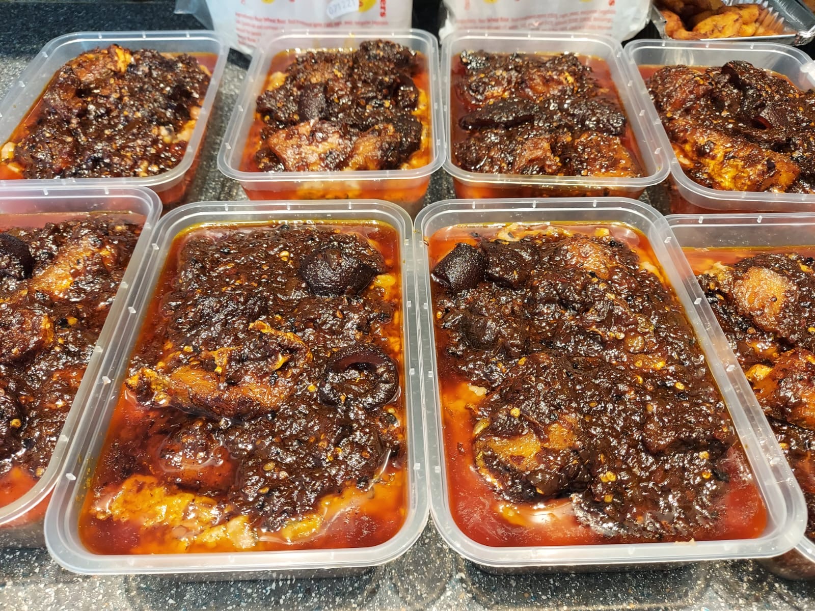 Containers of ewa agoyin: slow-cooked black-eye beans with a spicy palm oil sauce