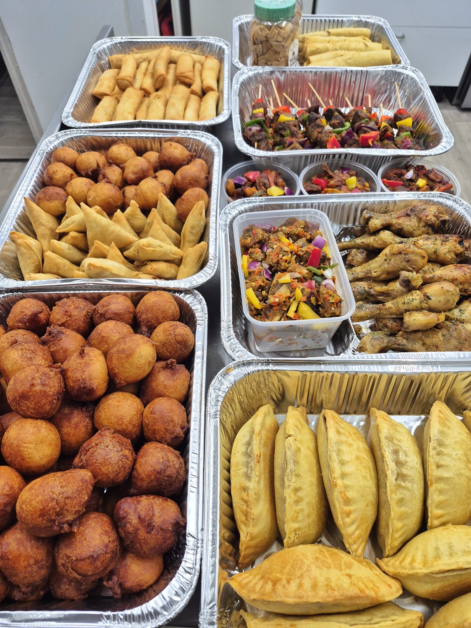 Large catering spread of puff-puff, meat pies, samosas, spring rolls, skewers and chicken