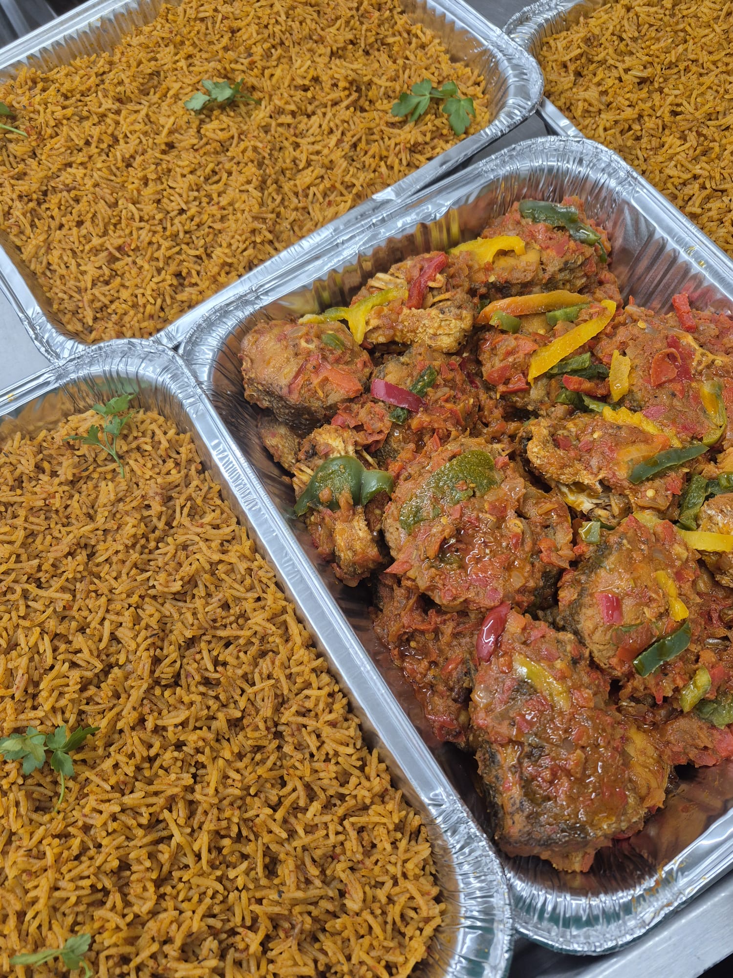 Catering trays of jollof rice and peppered fish