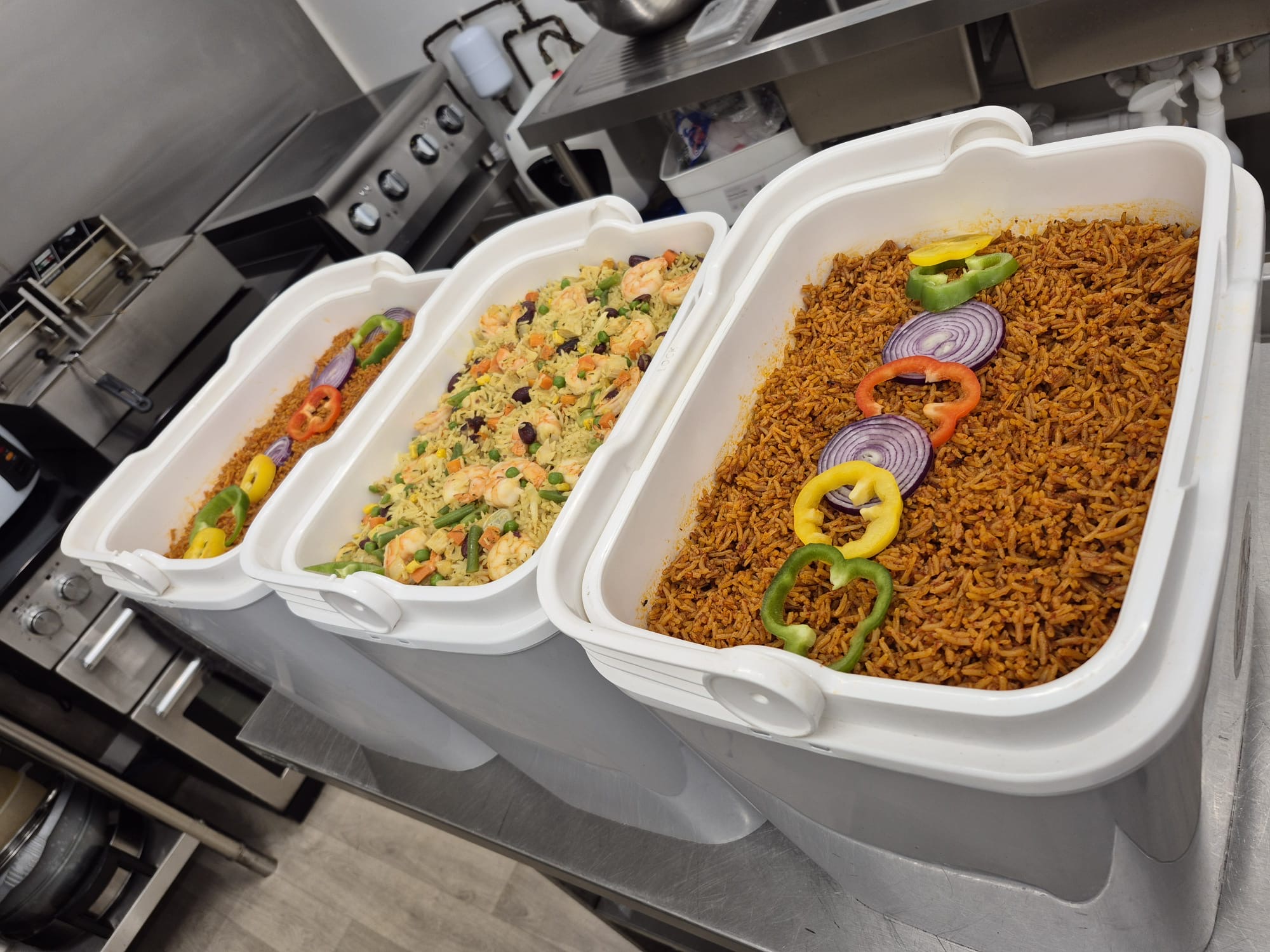 Catering warmers filled with jollof rice and Nigerian fried rice