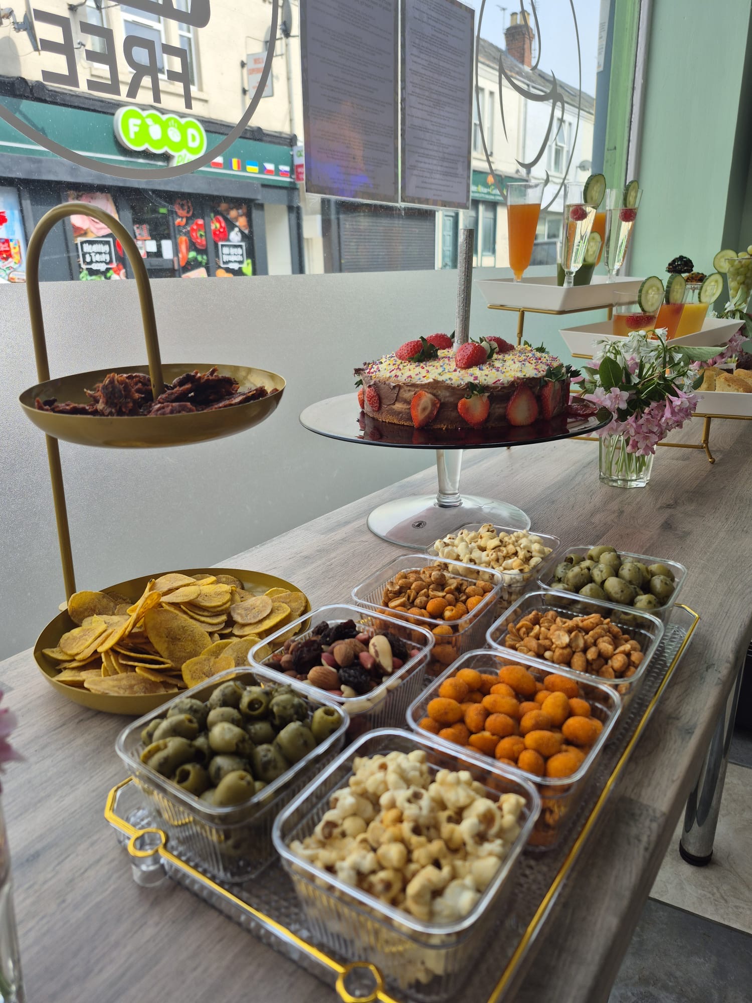 Celebration table with cake, plantain crisps, nuts and olives